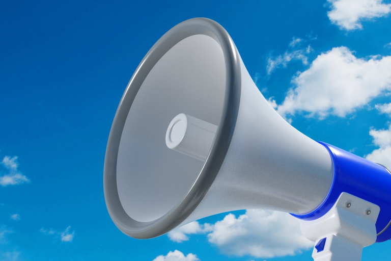 Close-up of a blue and white megaphone facing left against a clear sky with scattered clouds.