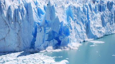 A large glacier with blue ice in the water.