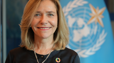 A woman smiling in front of a flag.
