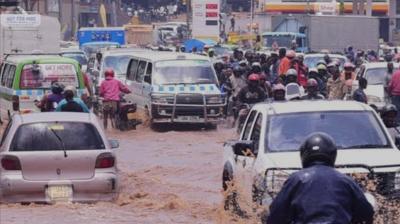 Traffic navigates through a flooded urban street.